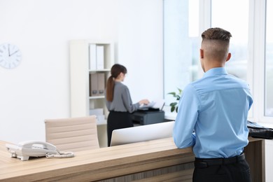 Photo of Professional receptionist working with client in office