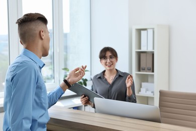 Photo of Professional receptionist working with client in office