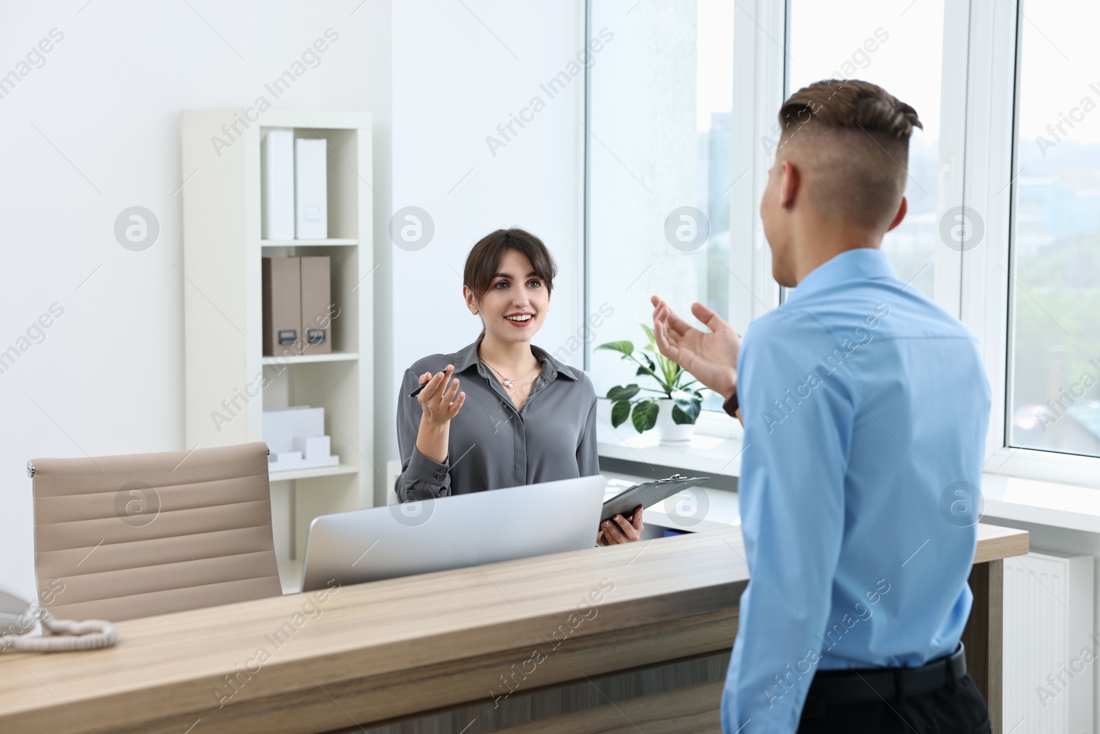 Photo of Professional receptionist working with client in office