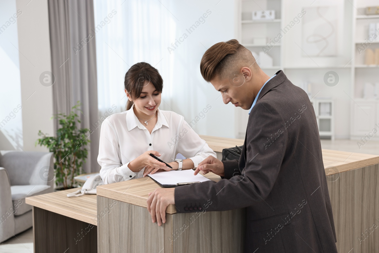 Photo of Professional receptionist working with client in office