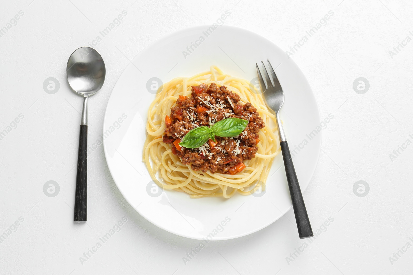 Photo of Delicious pasta bolognese and cutlery on white table, flat lay