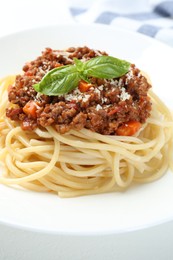 Photo of Tasty pasta bolognese with basil on white table, closeup