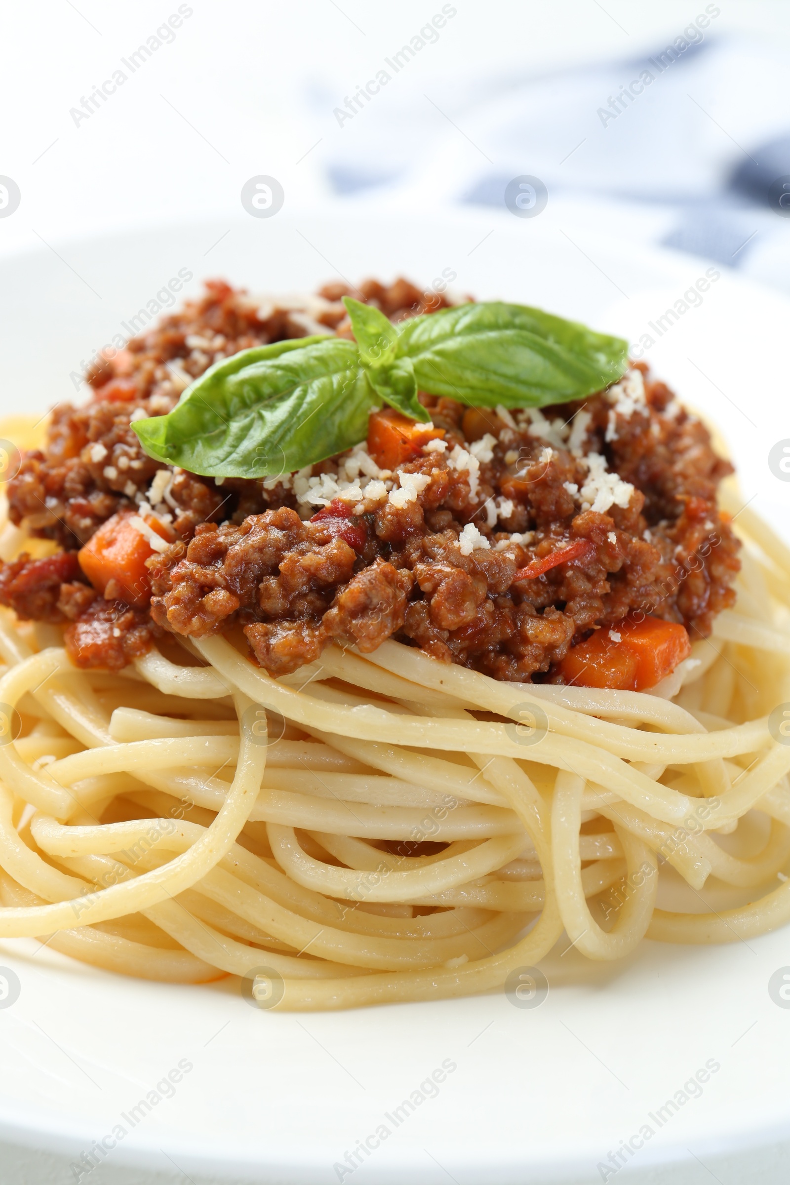 Photo of Tasty pasta bolognese with basil on white plate, closeup