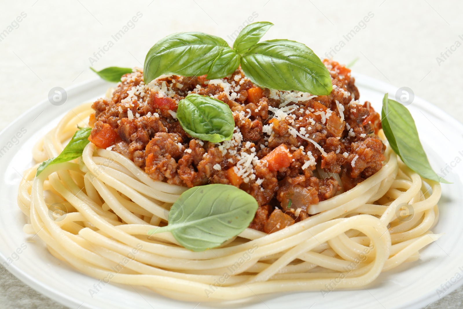 Photo of Tasty pasta bolognese with basil on white table, closeup