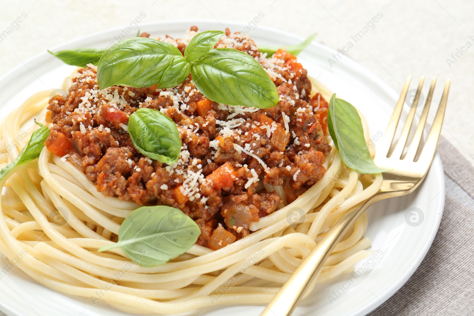 Photo of Delicious pasta bolognese with basil on light table, closeup