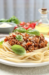 Photo of Tasty pasta bolognese with basil on white table, closeup