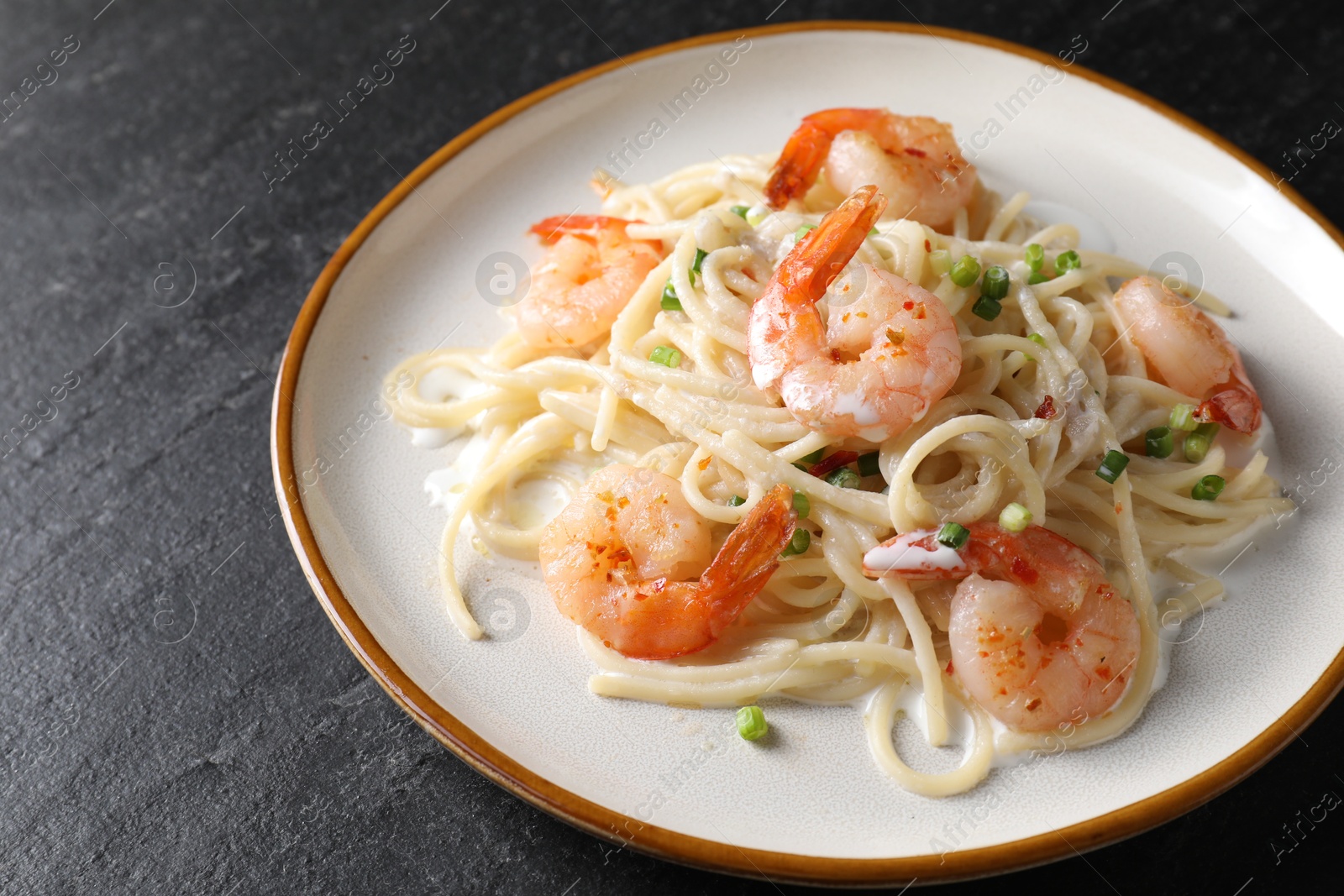 Photo of Delicious pasta with shrimps and green onion on black table, closeup