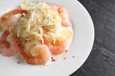 Photo of Delicious pasta with shrimps and cheese on black table, closeup