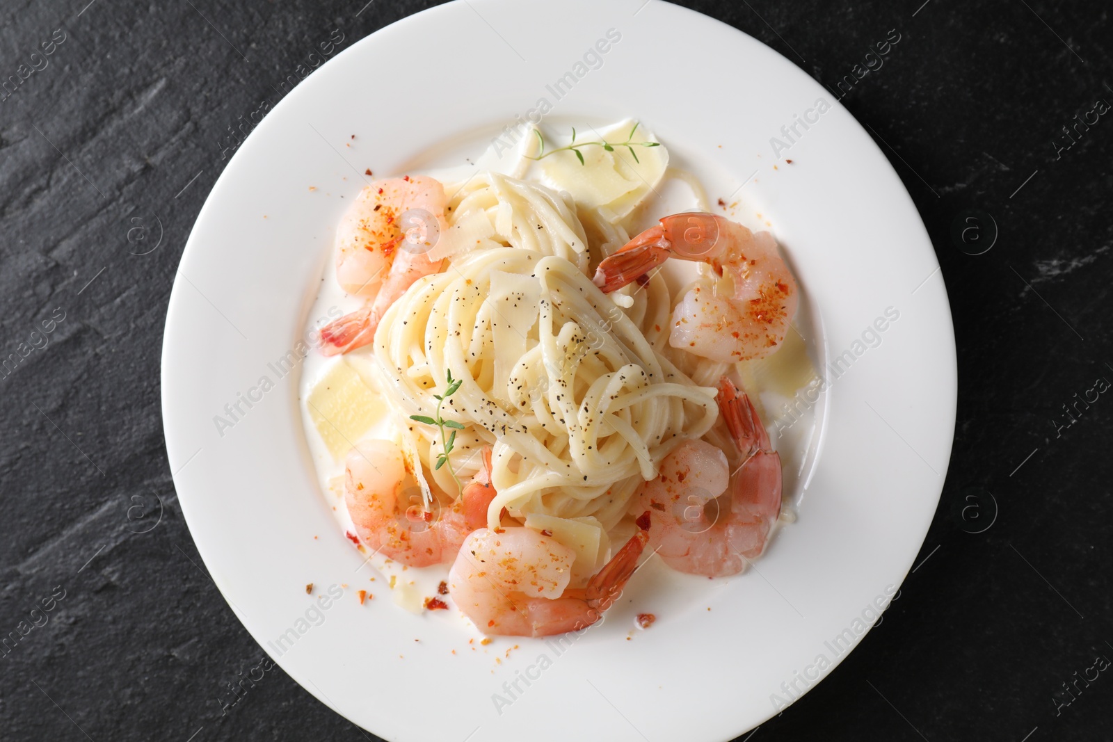 Photo of Delicious pasta with shrimps and cheese on black table, top view