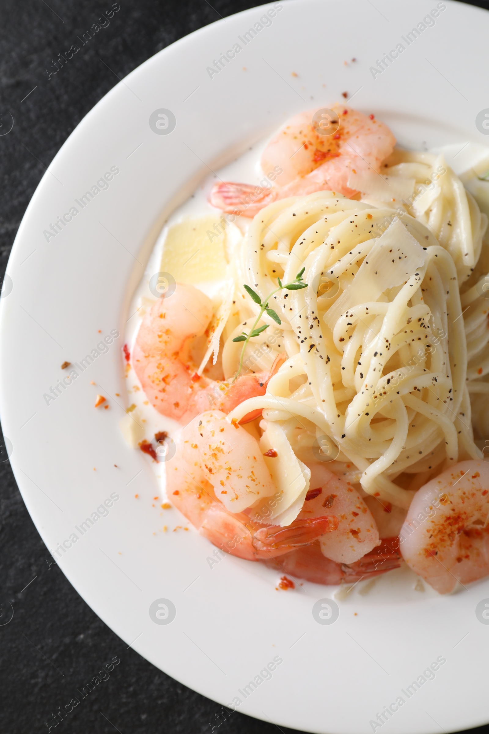 Photo of Delicious pasta with shrimps and cheese on black table, top view