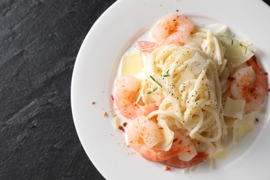 Photo of Delicious pasta with shrimps and cheese on black table, top view