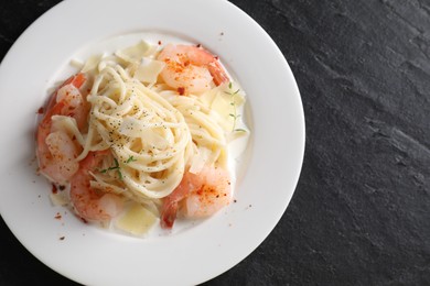 Photo of Delicious pasta with shrimps and cheese on black table, top view