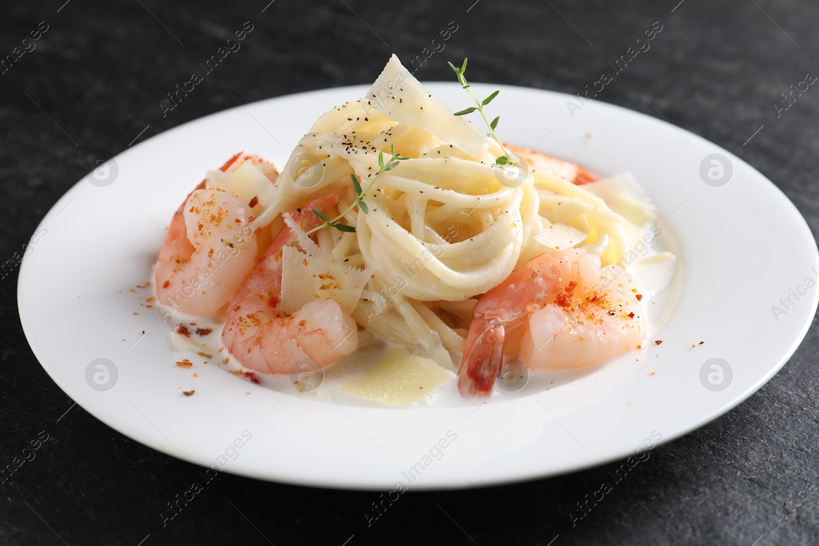 Photo of Delicious pasta with shrimps and cheese on black table, closeup