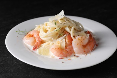 Photo of Delicious pasta with shrimps and cheese on black table, closeup