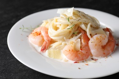 Photo of Delicious pasta with shrimps and cheese on black table, closeup