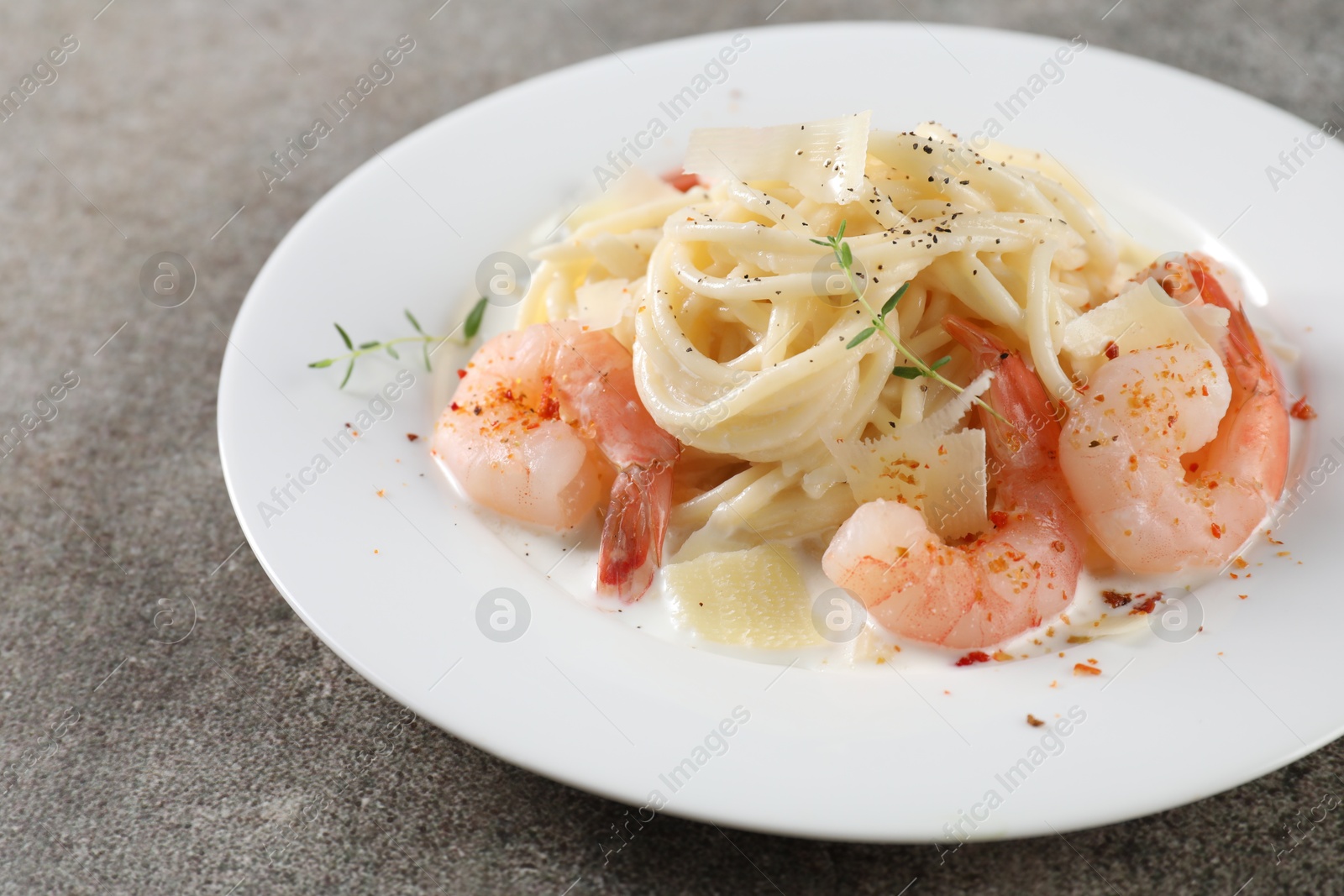 Photo of Delicious pasta with shrimps and cheese on grey table, closeup