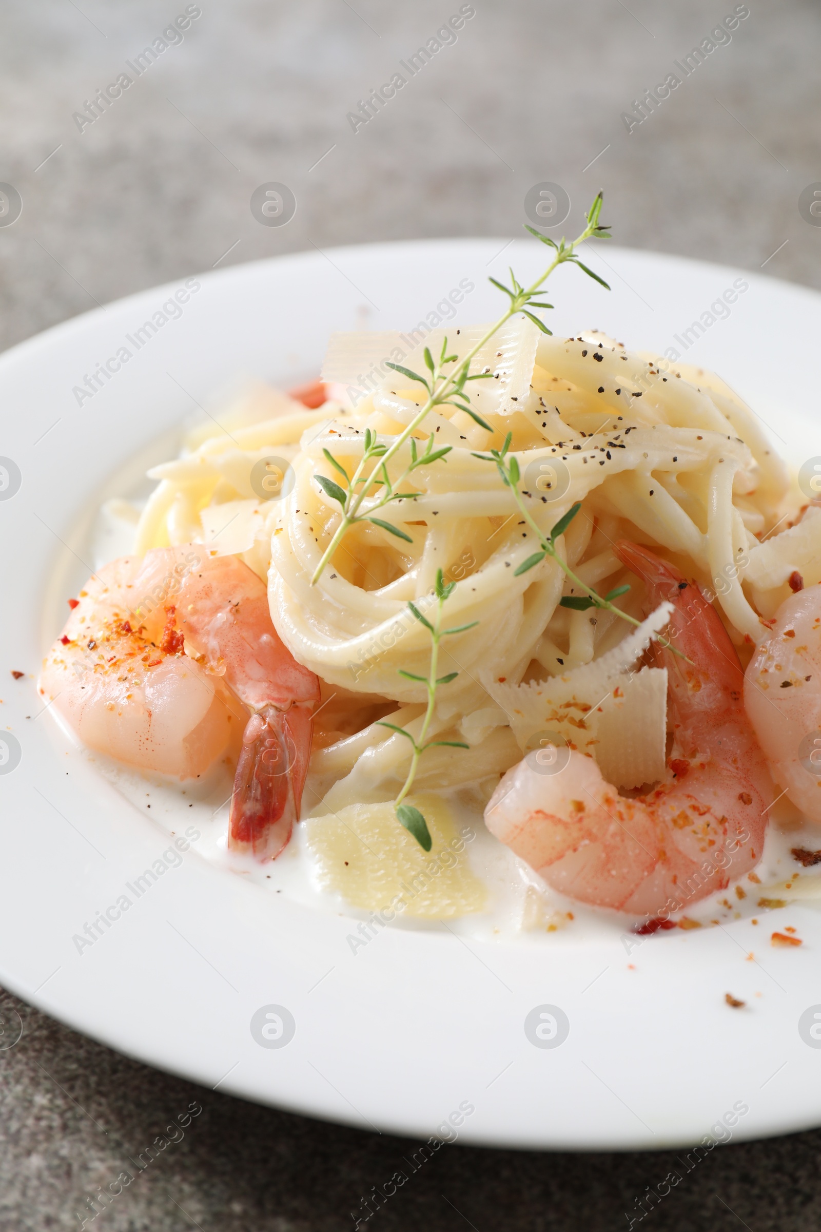 Photo of Delicious pasta with shrimps and cheese on grey table, closeup