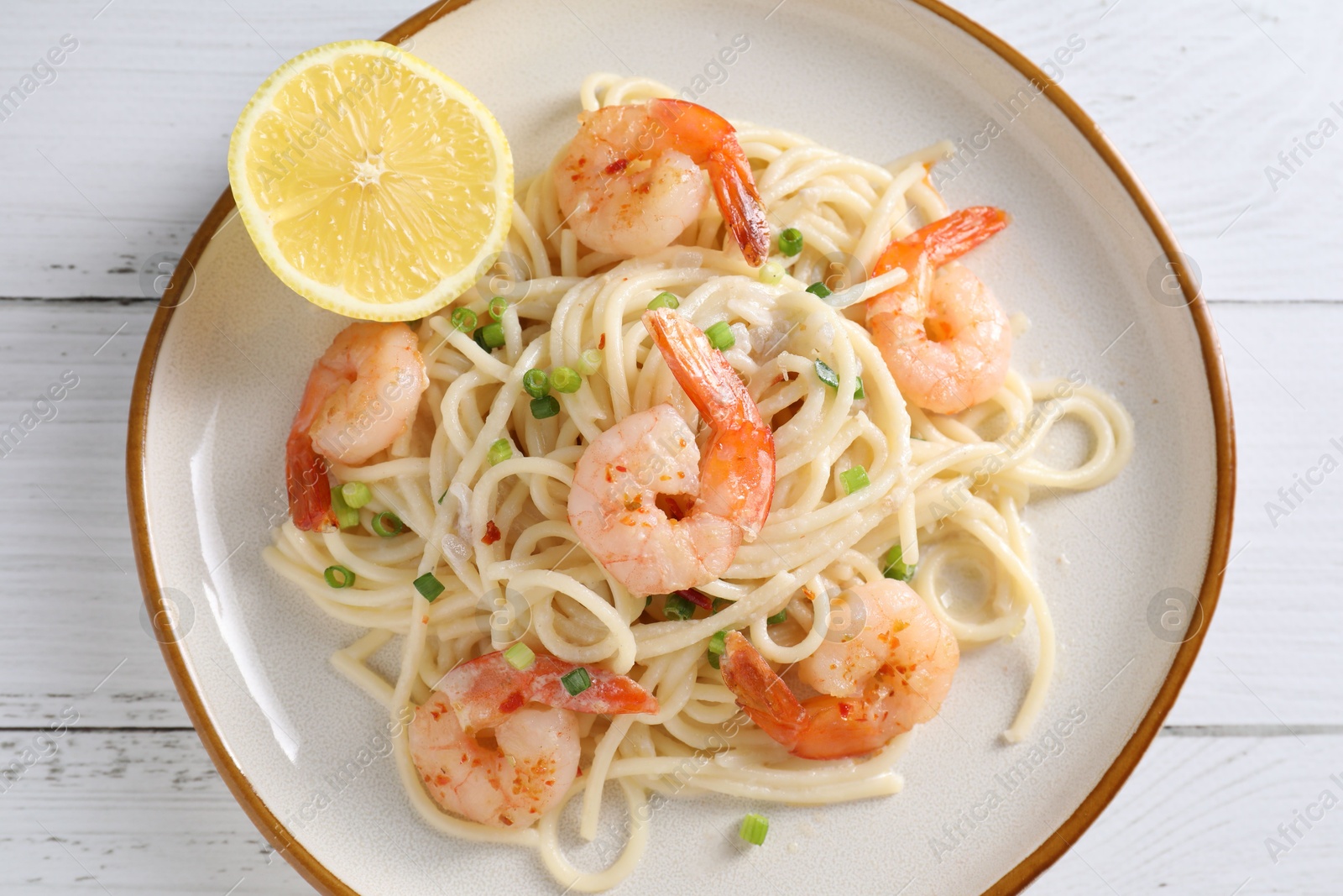 Photo of Delicious pasta with shrimps and green onion on white wooden table, top view