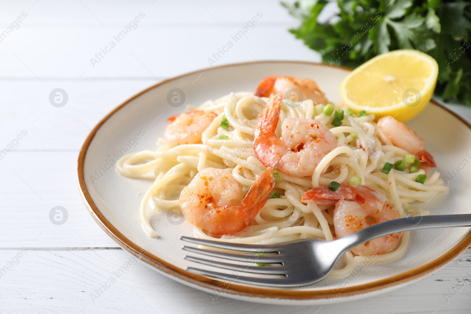 Photo of Delicious pasta with shrimps, green onion and fork on white wooden table, closeup