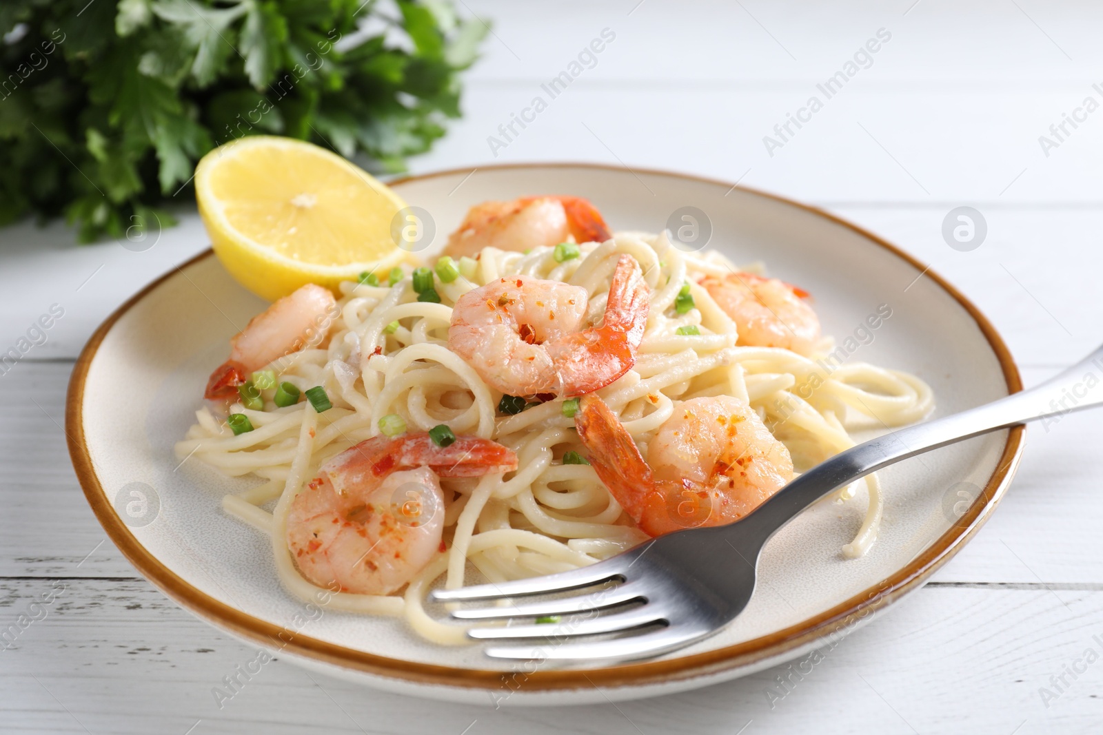 Photo of Delicious pasta with shrimps, green onion and fork on white wooden table, closeup