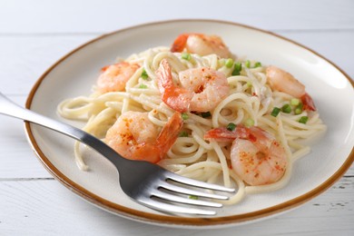 Photo of Delicious pasta with shrimps, green onion and fork on white wooden table, closeup