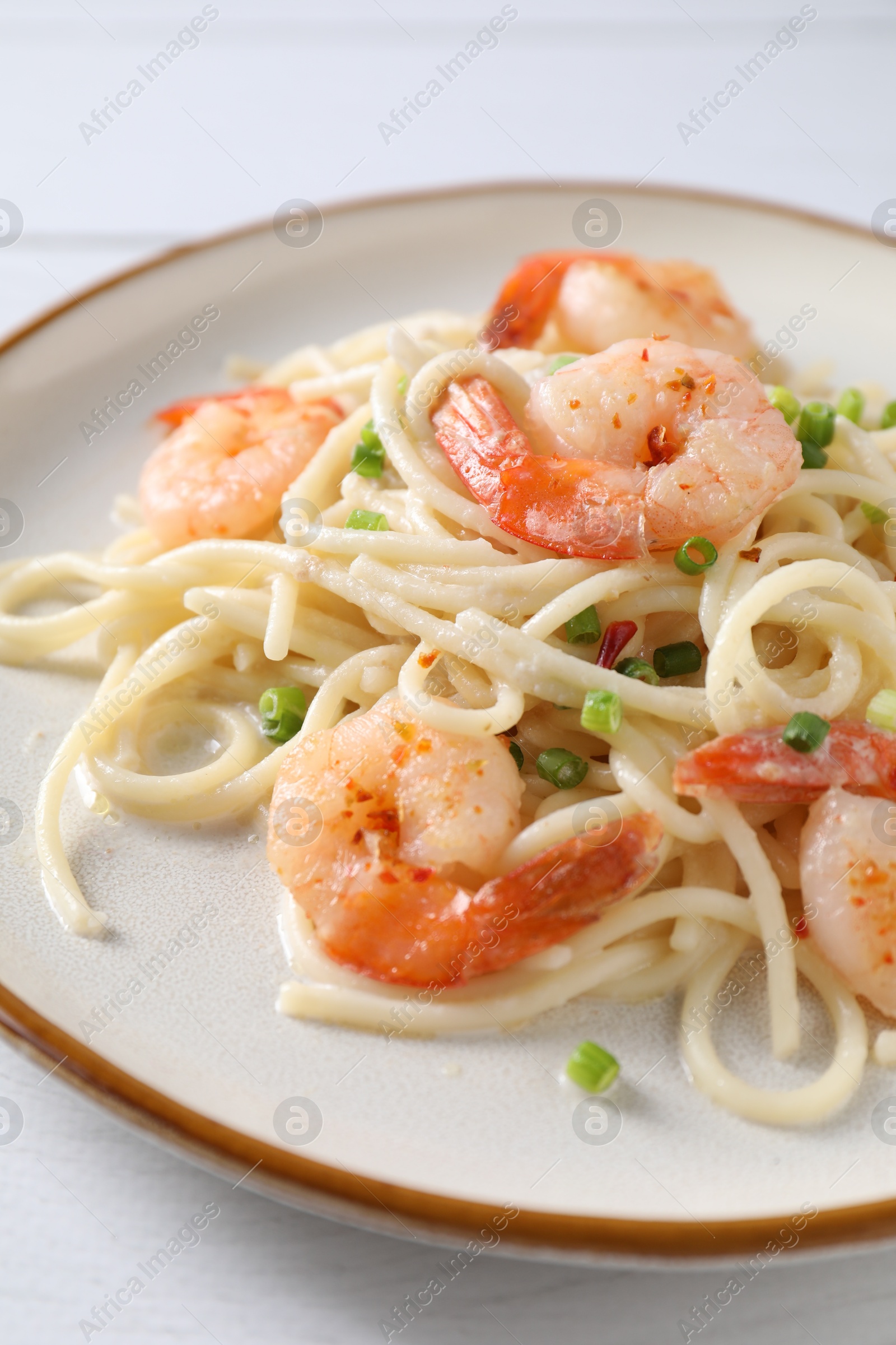 Photo of Delicious pasta with shrimps and green onion on white table, closeup