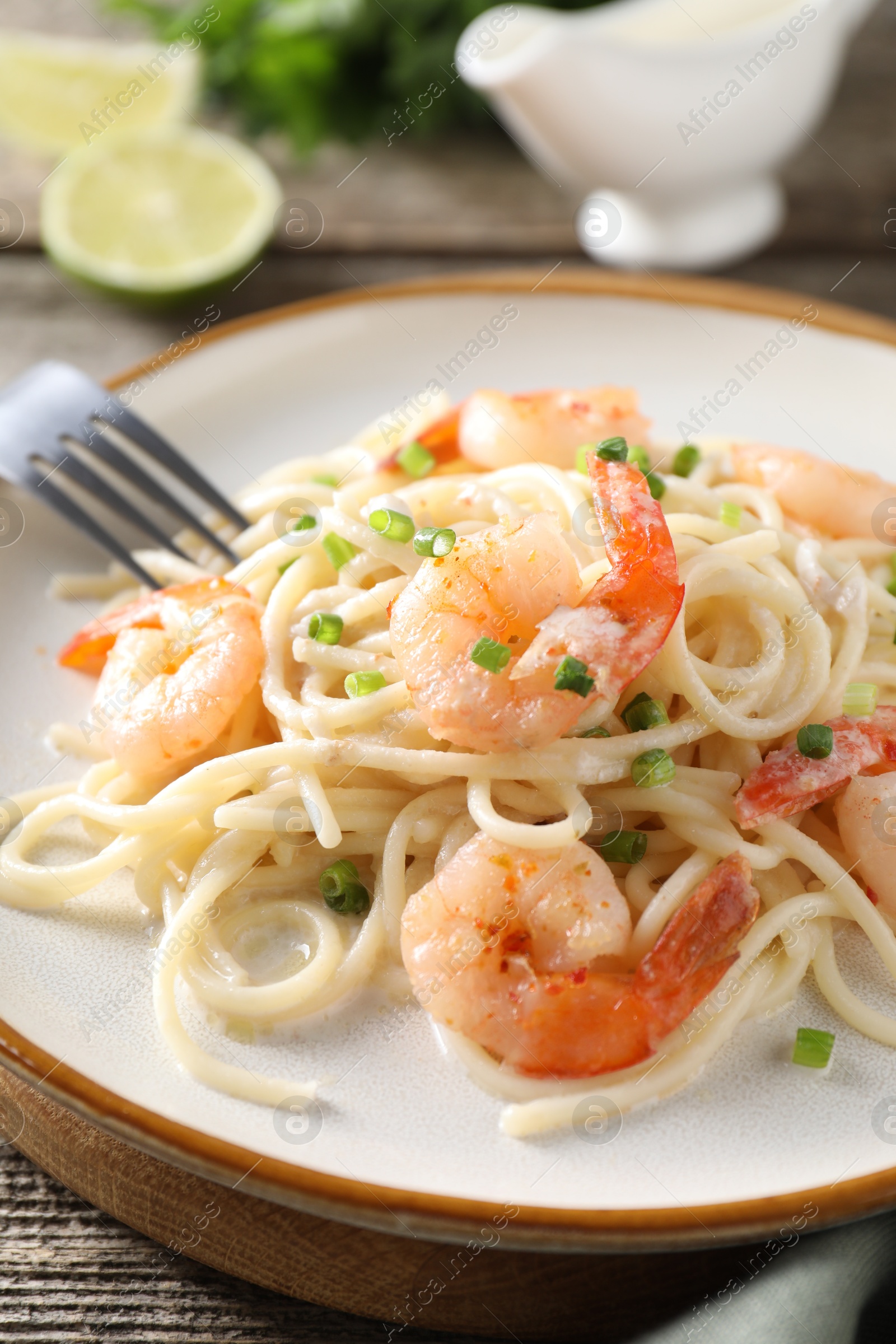 Photo of Delicious pasta with shrimps and green onions on wooden table, closeup