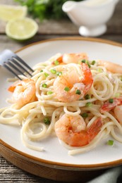 Photo of Delicious pasta with shrimps and green onions on wooden table, closeup