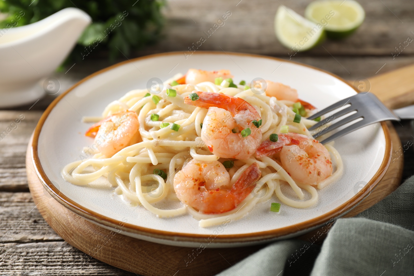 Photo of Delicious pasta with shrimps and green onions on wooden table, closeup