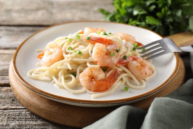 Photo of Delicious pasta with shrimps and green onions on wooden table, closeup