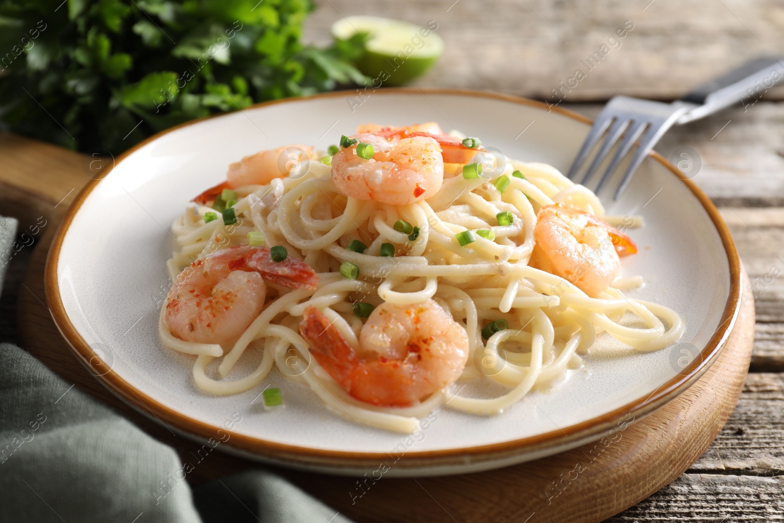 Photo of Delicious pasta with shrimps and green onions on wooden table, closeup