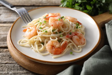 Delicious pasta with shrimps and green onions on wooden table, closeup