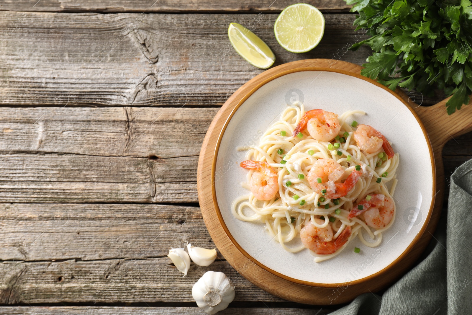 Photo of Delicious pasta with shrimps, lime and spices on wooden table, flat lay. Space for text