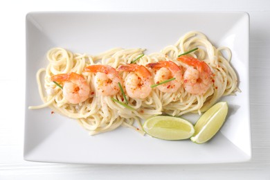 Photo of Delicious pasta with shrimps and lime on white wooden table, top view