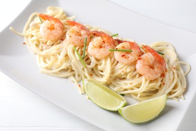 Photo of Delicious pasta with shrimps and lime on white wooden table, closeup