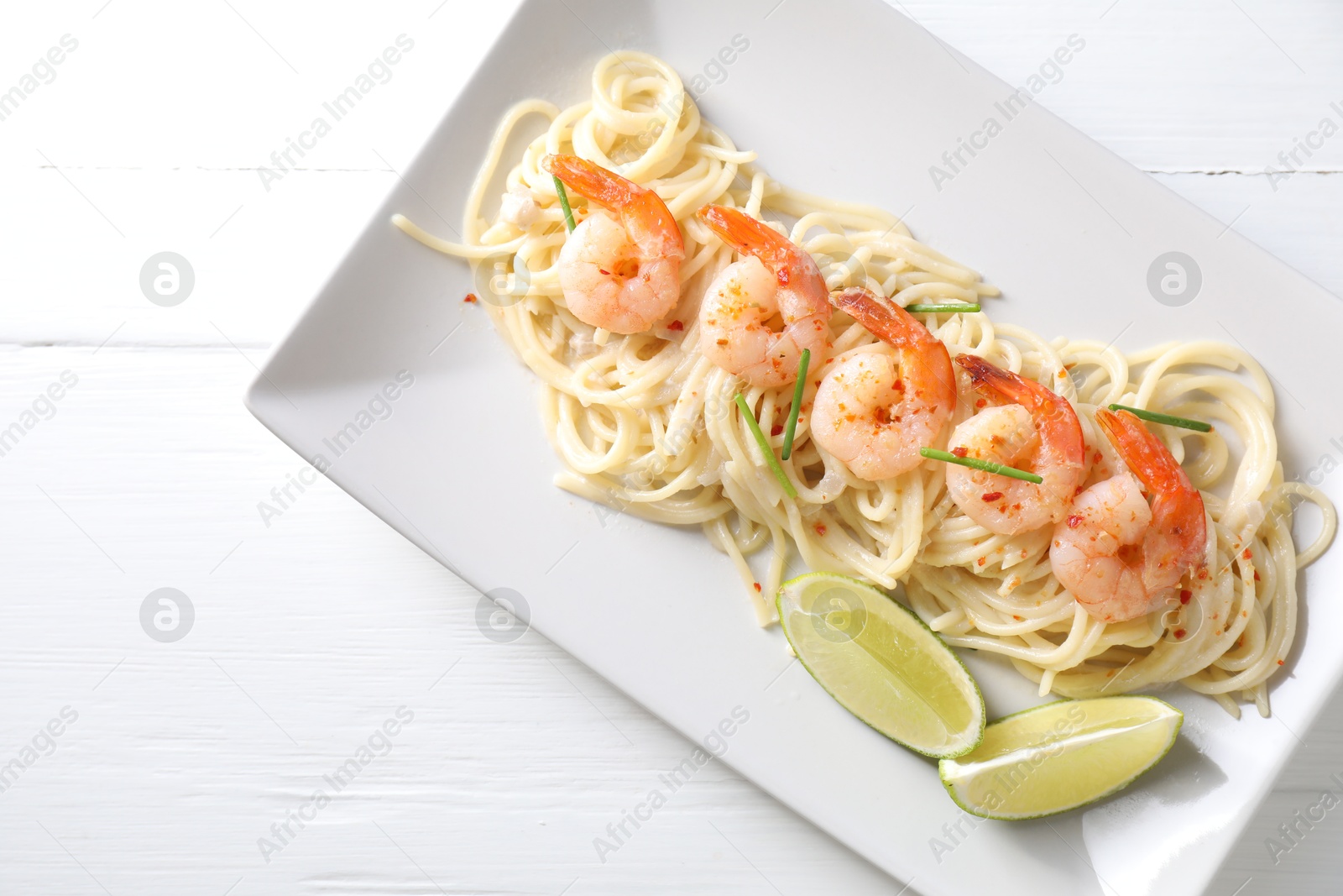 Photo of Delicious pasta with shrimps and lime on white wooden table, top view