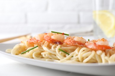 Photo of Delicious pasta with shrimps and green onions on white table, closeup