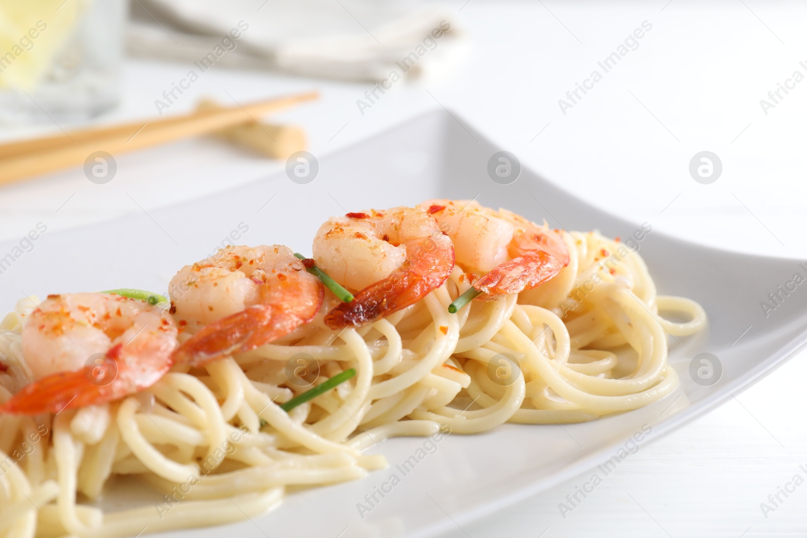 Photo of Delicious pasta with shrimps and green onions on white table, closeup