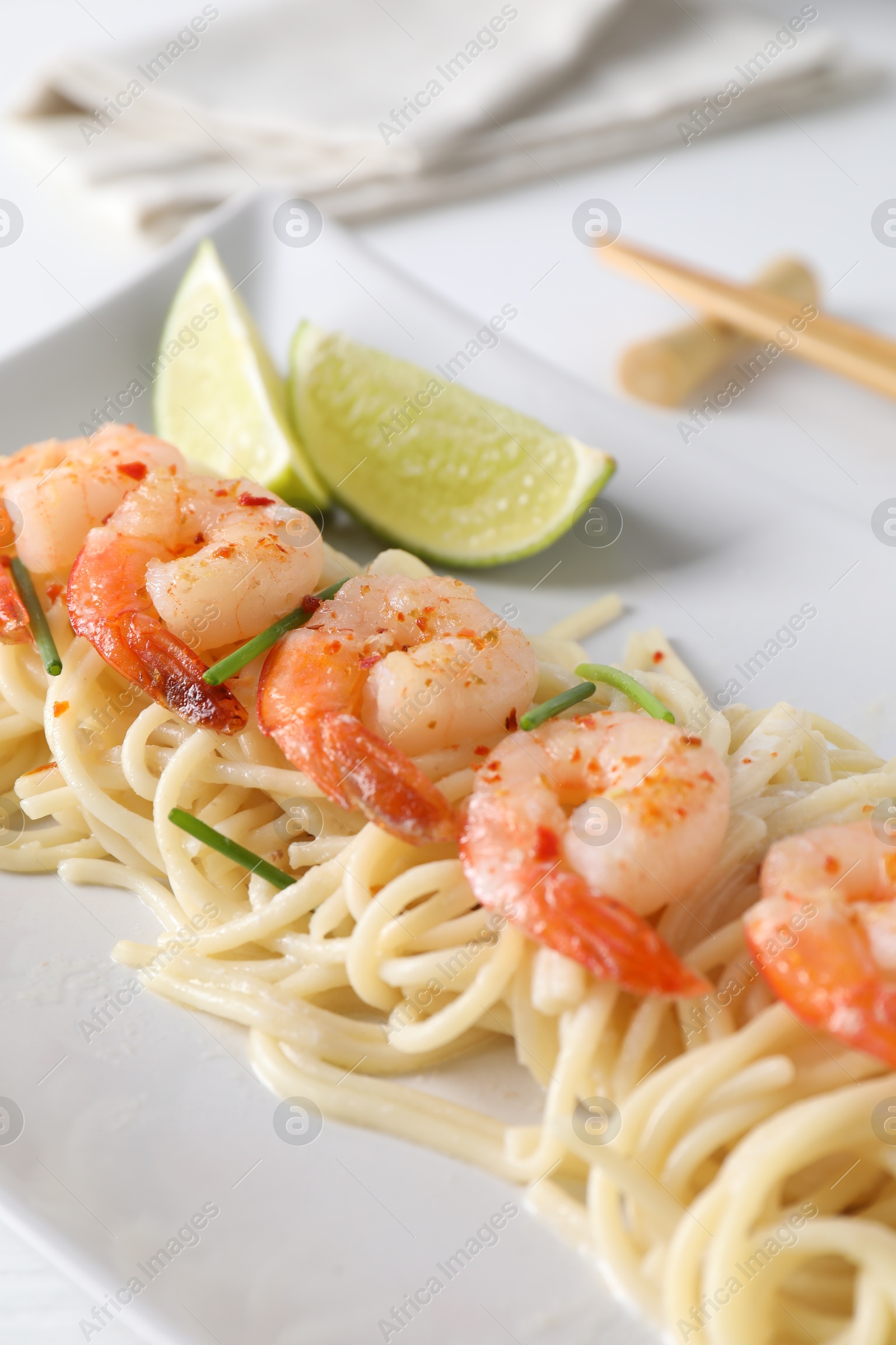 Photo of Delicious pasta with shrimps, green onions and lime on table, closeup