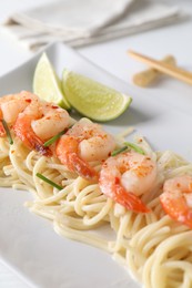 Photo of Delicious pasta with shrimps, green onions and lime on table, closeup