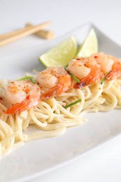 Photo of Delicious pasta with shrimps, green onions and lime on white table, closeup