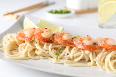 Photo of Delicious pasta with shrimps, green onions and lime on white table, closeup