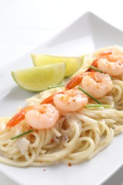 Photo of Delicious pasta with shrimps, green onions and lime on table, closeup