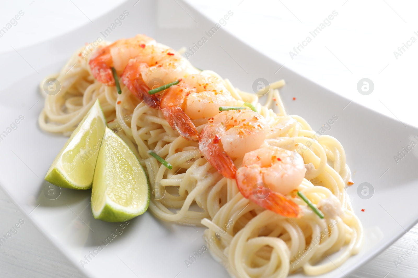 Photo of Delicious pasta with shrimps, green onions and lime on table, closeup