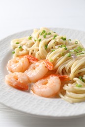 Photo of Delicious pasta with shrimps and green onions on white table, closeup