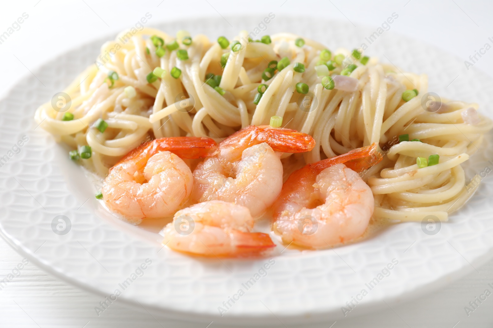 Photo of Delicious pasta with shrimps and green onions on white table, closeup