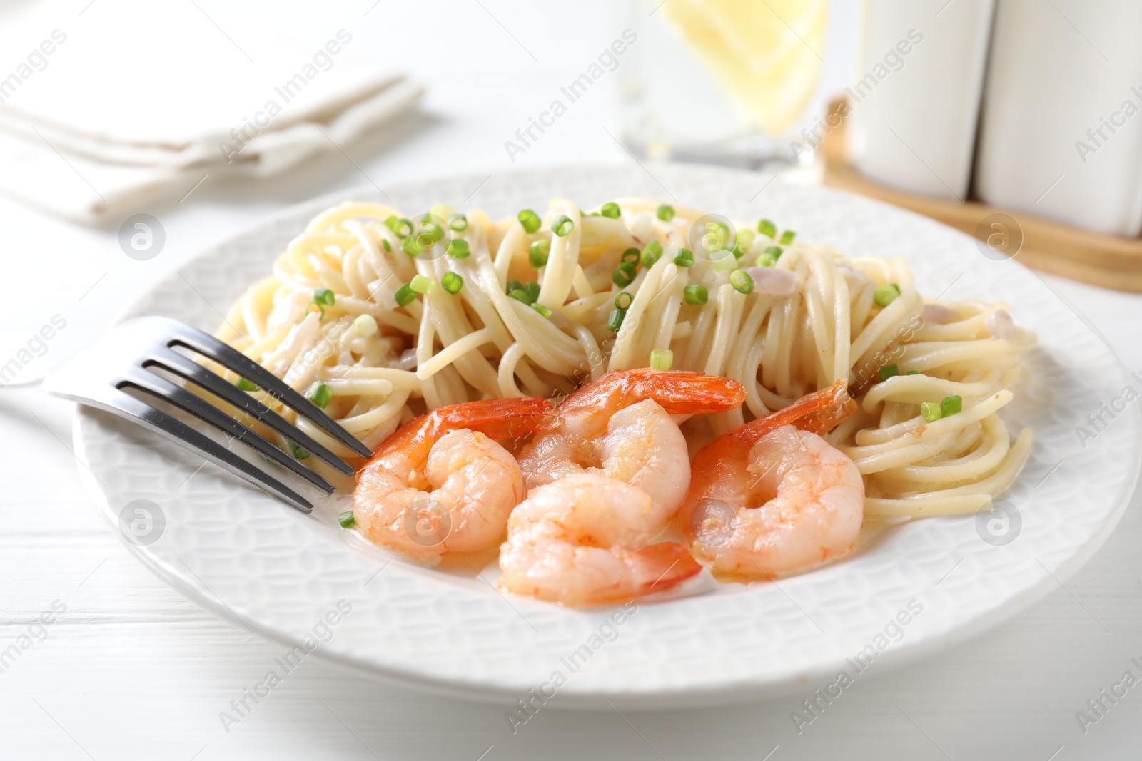 Photo of Delicious pasta with shrimps and green onions on white wooden table, closeup