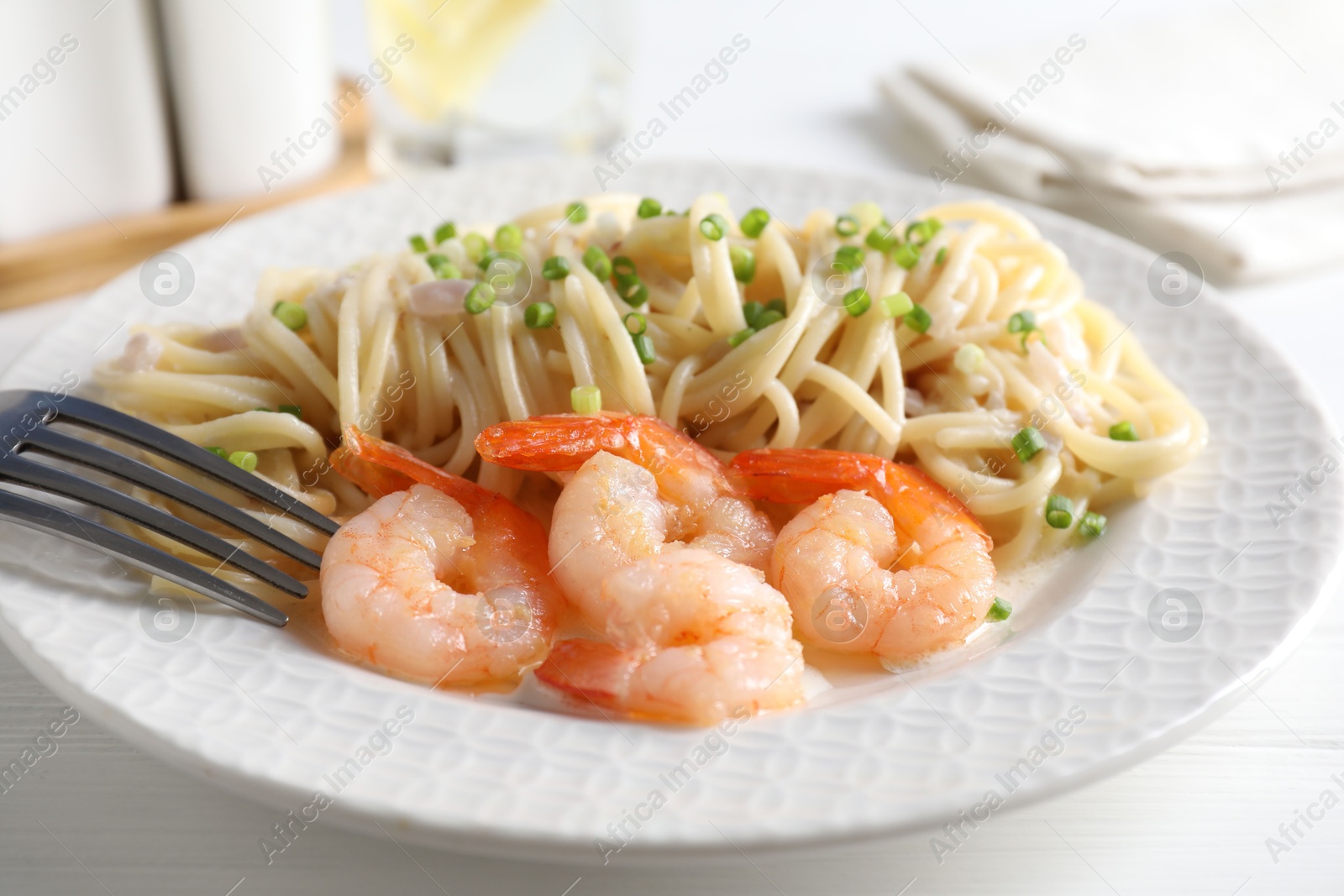 Photo of Delicious pasta with shrimps and green onions on white table, closeup