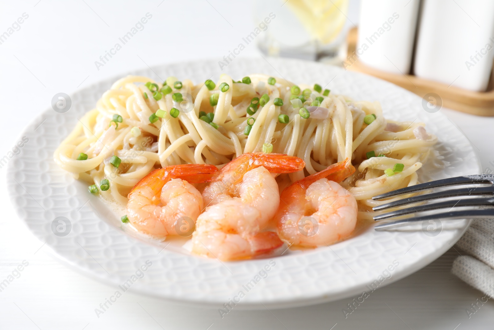 Photo of Delicious pasta with shrimps and green onions on white table, closeup