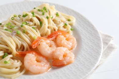 Photo of Delicious pasta with shrimps and green onions on white table, closeup